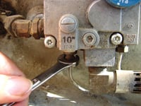 An end wrench is used to remove and install a thermocouple attachment at the gas valve.
