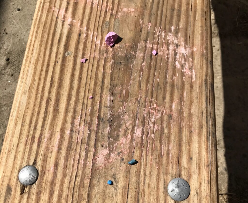 picnic table seat covered in chalk markings and bits