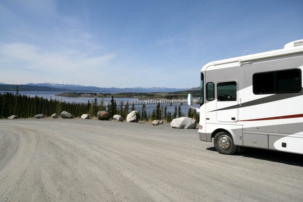 Class A RVs parked on the side of a dirt road with a view of a river