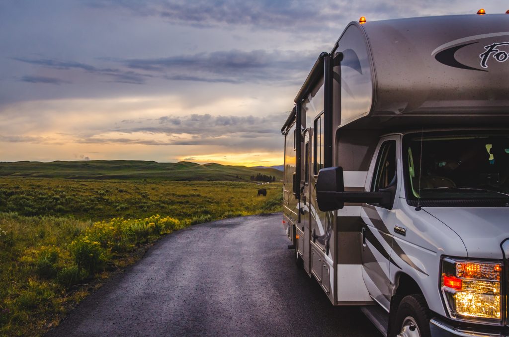 Motorhome RV on a dirt road with the sun setting behind it