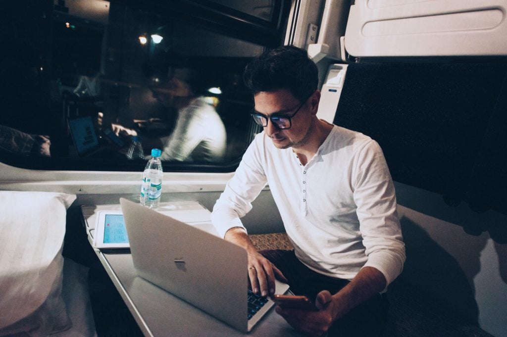 young man working on a laptop while traveling