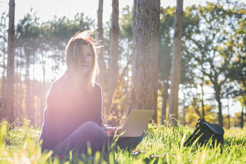 woman using a laptop sitting outside in a forest