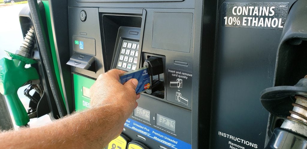 man holding credit card to pay for diesel at a truck stop. Buying fuel can help lower the cost of truck stop showers. 