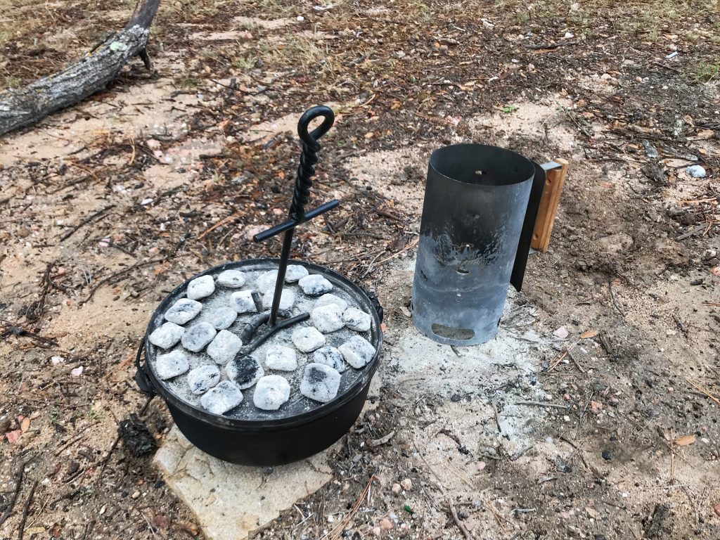 Dutch oven outside with coals on top cooking Thanksgiving dinner rolls. A dutch oven is a great method to use when RV cooking. 
