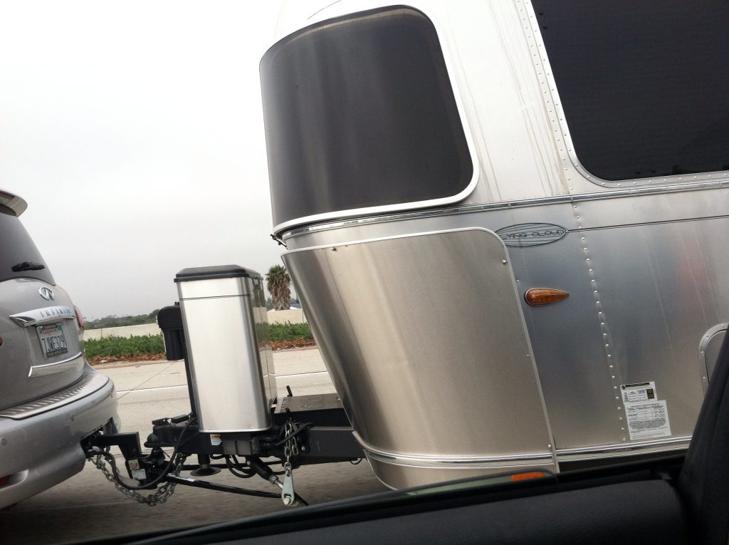 An airstream RV towing down the road with weight distribution hitch and chains for safety 