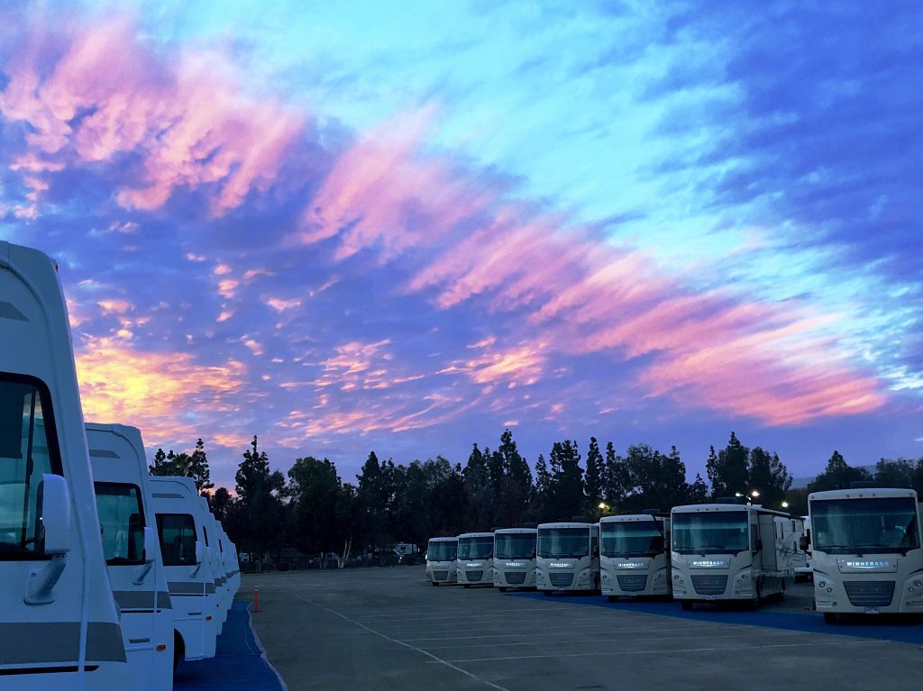 Row of motorhome RVs with a purple sunset in the background