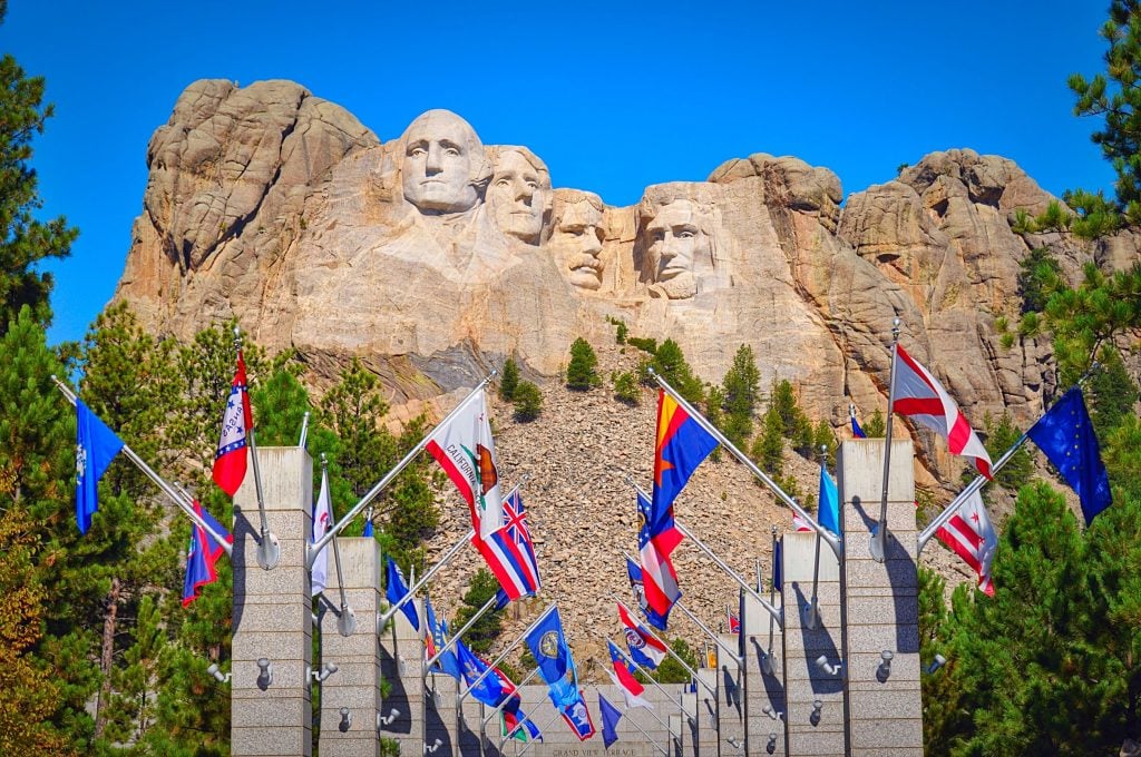 Picture of Mount Rushmore with different state flags lining the walkway. South Dakota is one of the best states for RV domicile. 
