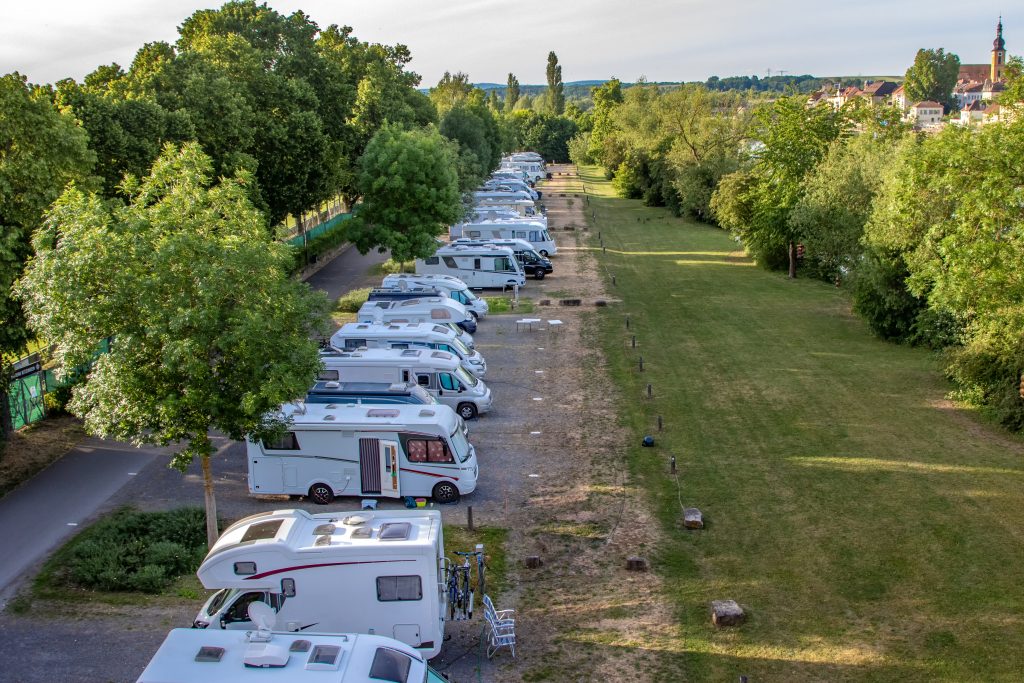 A row of RVs on pavement with grass and trees surrounding them. If you're asking where to buy an RV, a private seller could be an option. 