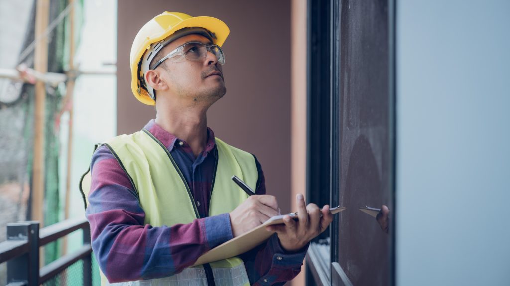 Man in a hard hat and a notepad inspecting a used RV window. If you're asking where to buy an RV and you opt for private seller, be sure to get a certified inspector. 