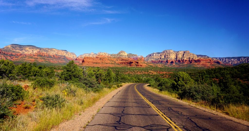 An open road leading to Sedona with red rocks in the background. You can get views like this when boondocking in Arizona. 