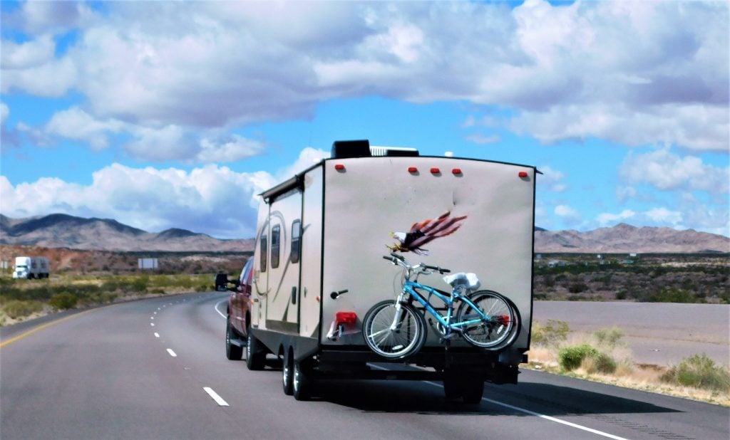 A travel trailer with bikes on the back being towed down the highway