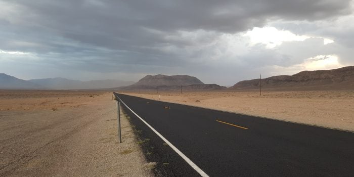 driving through death valley with storm clouds in sky