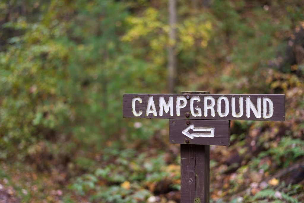wooden campground sign with arrow. Booking your first site is part of how to prepare for full-time RV living