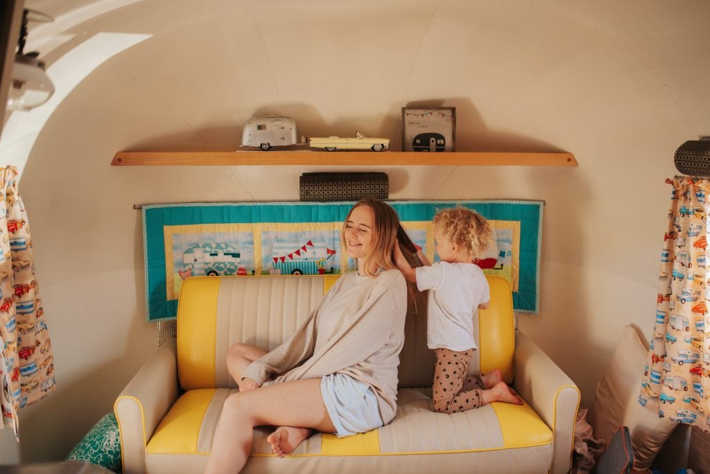 Mother getting her hair braided by her child while sitting in an RV