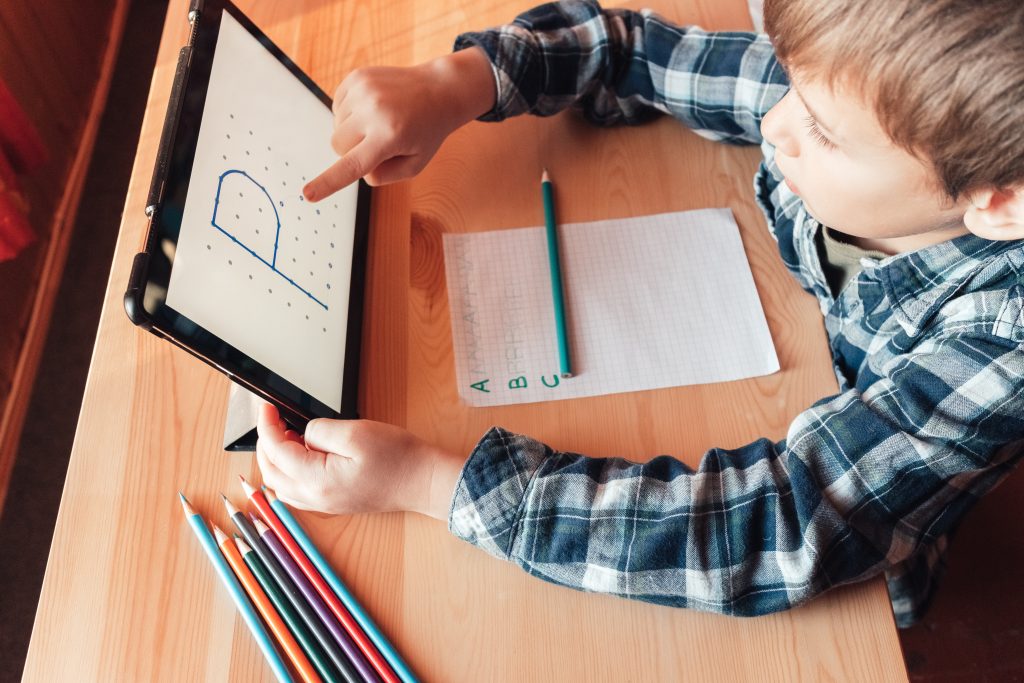 MODERN CHILD USES APP ON TABLET TO STUDY AND DRAW AT HOME