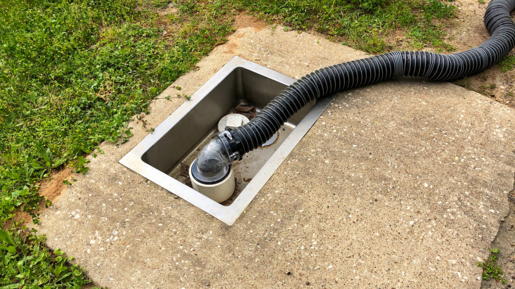 An RV sewer hose attached to a dump station. 