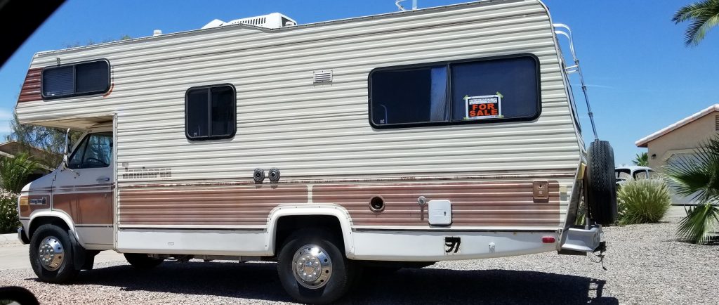 An older RV parked on the road with a for sale sign in the window. Buying an a fixer upper is one of the common RV buying mistakes. 