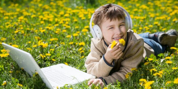 boy in field with headphones and laptop
