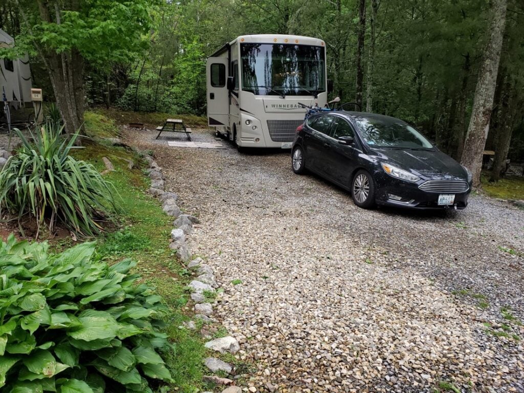 Class A motorhome on gravel site surrounded by trees