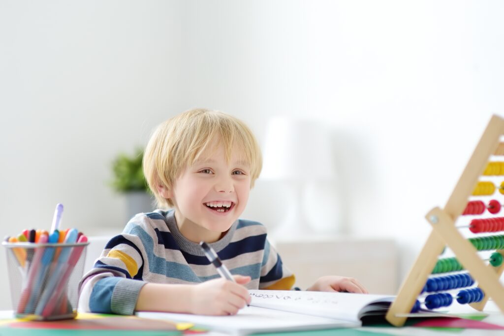 Little boy smiling while doing math at home 