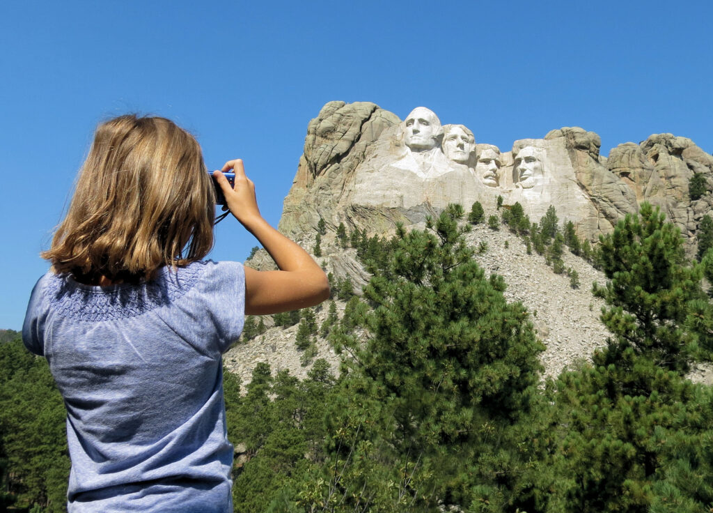 A child taking a picture of Mount Rushmore. An educational stop for one of the best RV trips for families