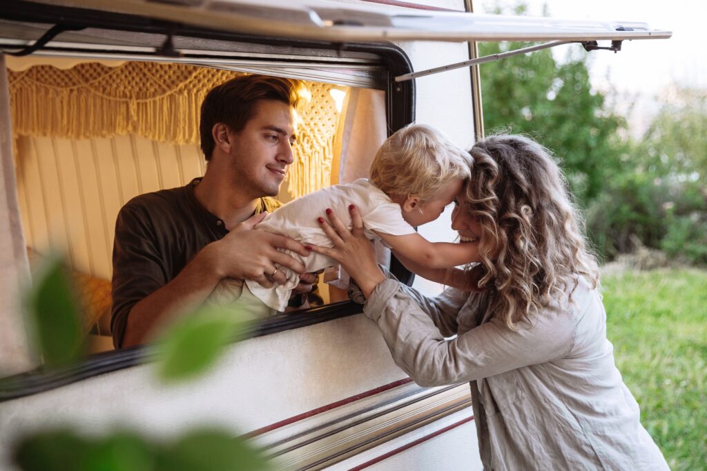 A man in an RV handing his child to his wife out the big window
