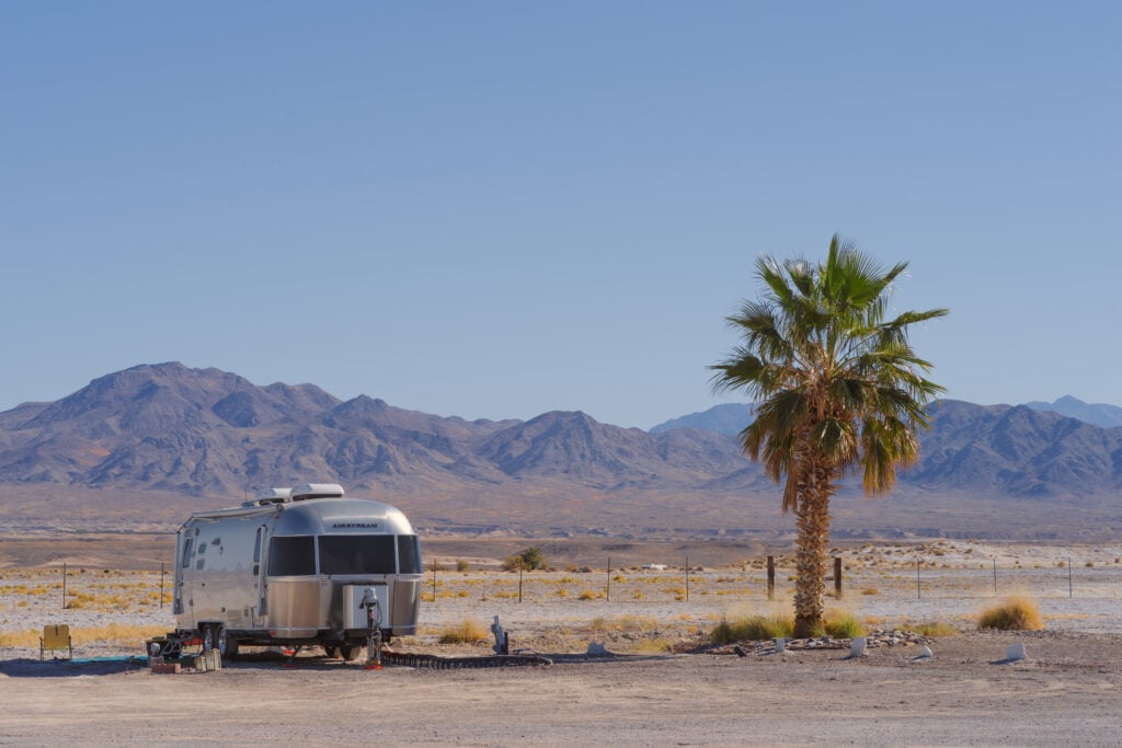 Airstream - go RVing in desert by palm tree