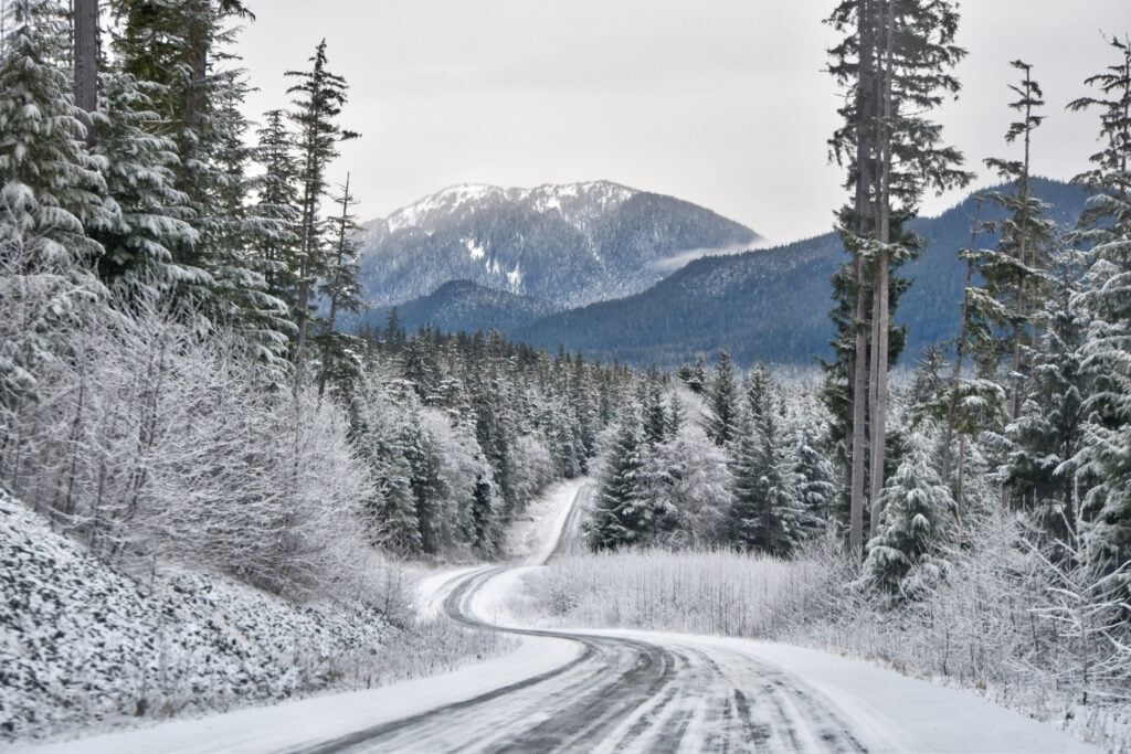 A snow covered road in Alaska. Many people are worried about the driving conditions when asking can you drive an RV to Alaska