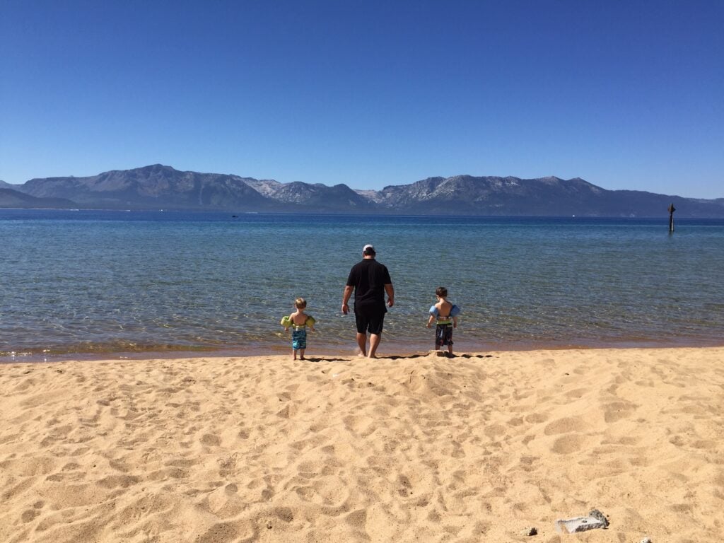 A father and his two children walking on the sand, playing on their lake Tahoe camping trip 