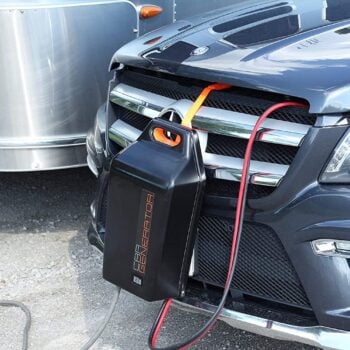 A CarGenerator backup power supply hangs from the grill of a vehicle.
