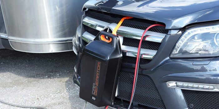 A CarGenerator backup power supply hangs from the grill of a vehicle.