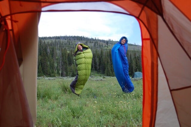 Two people in sleeping bags jumping outside in them, an item they got off their Primitive Camping Checklist