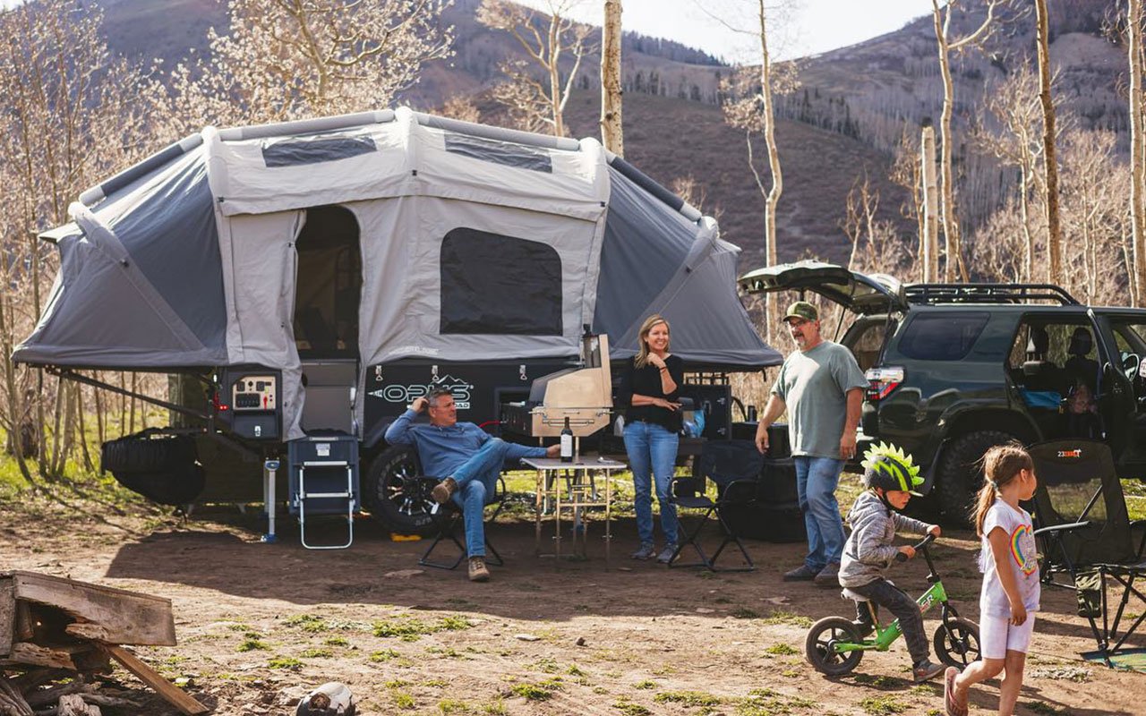 family of 5 camping outdoors in pop-up tent trailer