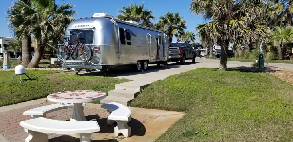 picnic table in foreground with palm tress and airstream RV