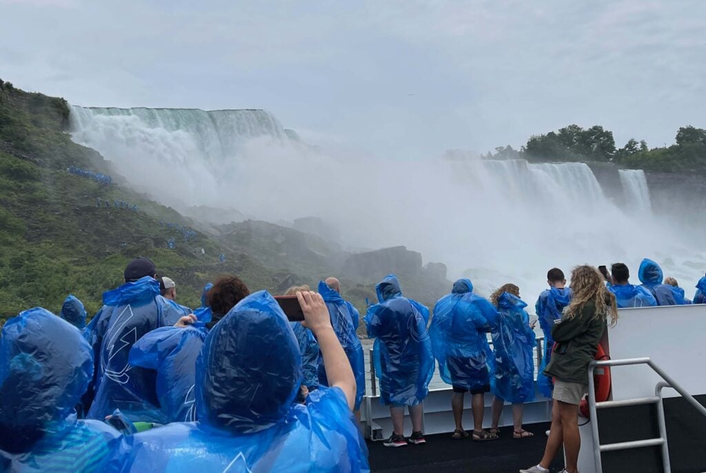 People in blue raincoats taking pictures of Niagara Falls. - living in an RV year round allows you more experiences like this