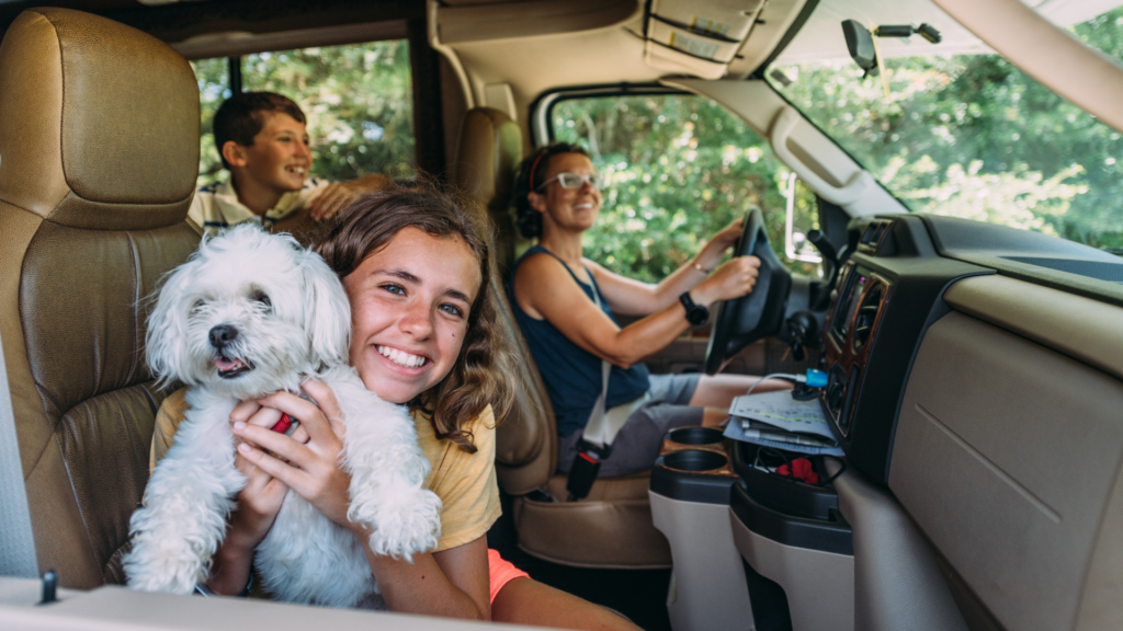 A mom driving an RV with her two children and a dog. Learning how to travel full time with a family is easy.