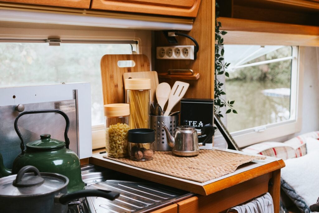 Interior shot of an RV kitchen with pots on the stove. Having good organization is an important full-time stationary RV living tips.