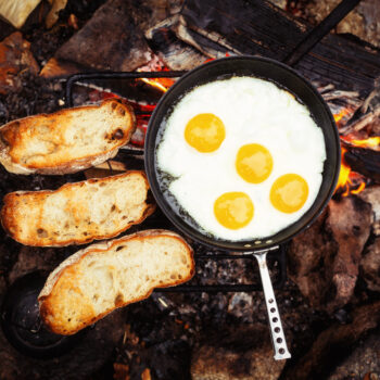 eggs in frying pan - campfire breakfast ideas - on grate over the fire