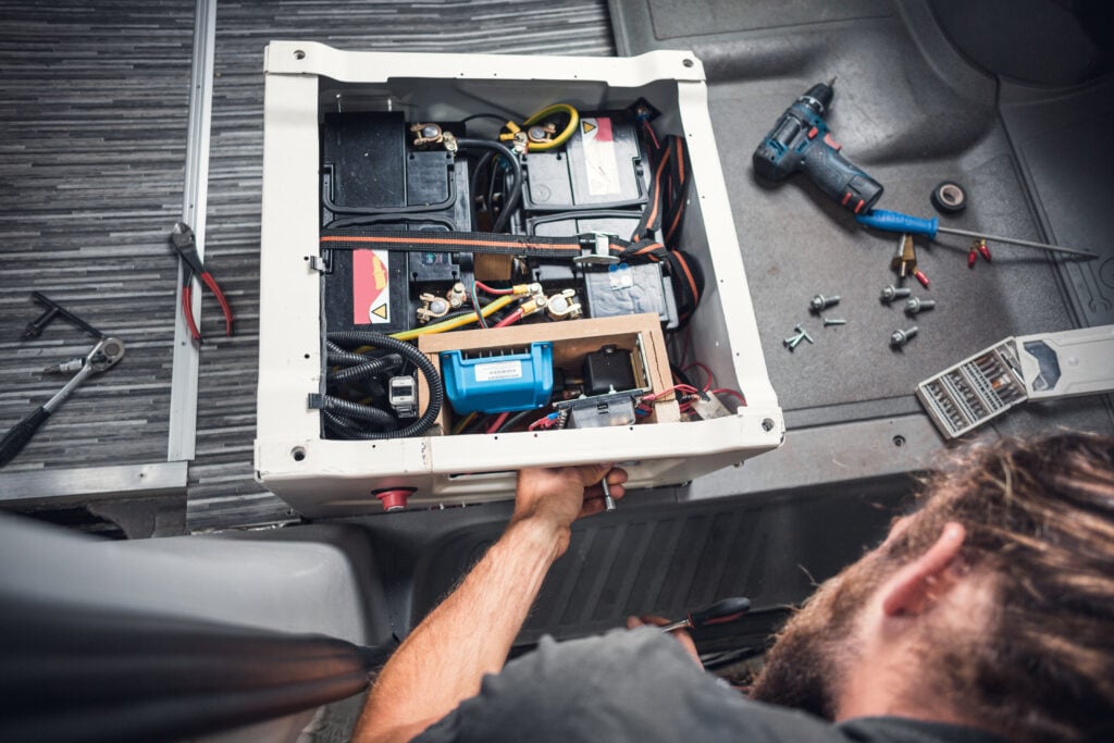 A man installing extra RV batteries in his van. 