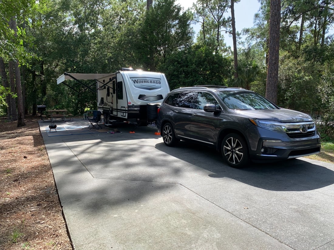 travel trailer on cement pad surrounded by trees