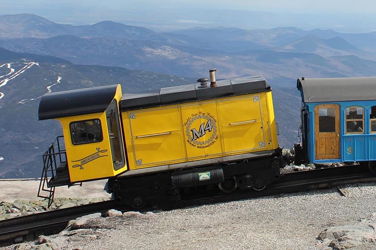 yellow train caboose with mountains in the background - one of our favorite RV trip ideas
