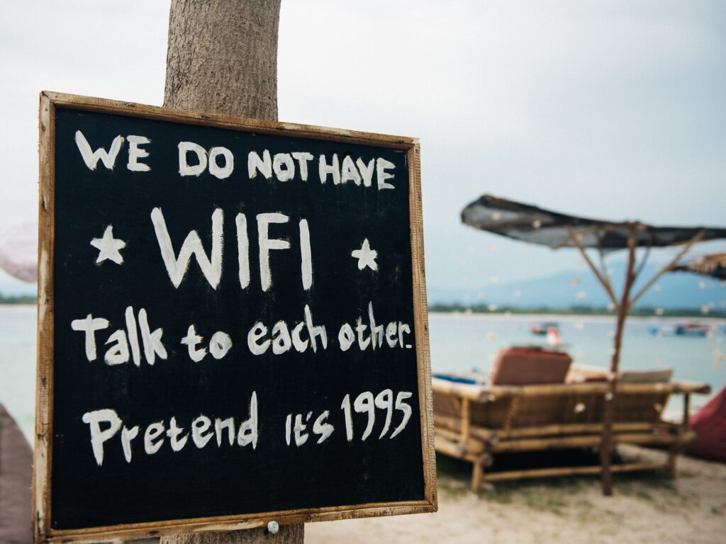 A sign at a campground in front of a beach saying "we do not have WIFI" 