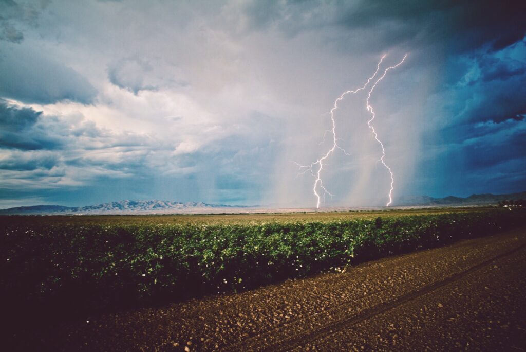 An open field with lightning striking the ground. An emergency radio is one of our recommended boondocking must haves. 