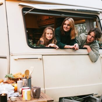 mother, daughter, and son looking out window of trailer