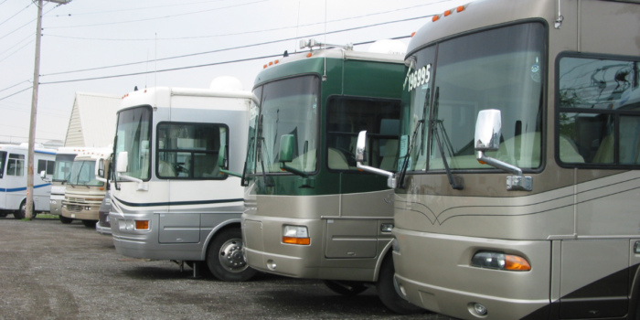 Row of motorhomes parked side by side in a parking lot - how does selling an RV On consignment work?
