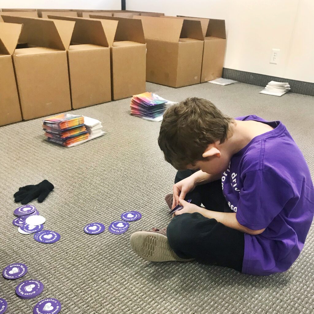 young boy sitting on the floor with purple shirt sorting stickers