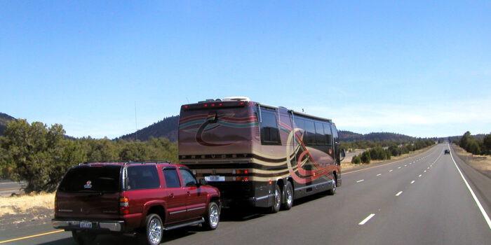 diesel pusher motorhome towing a car on the highway