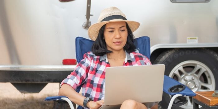 Woman uses laptop outside of Airstream camper