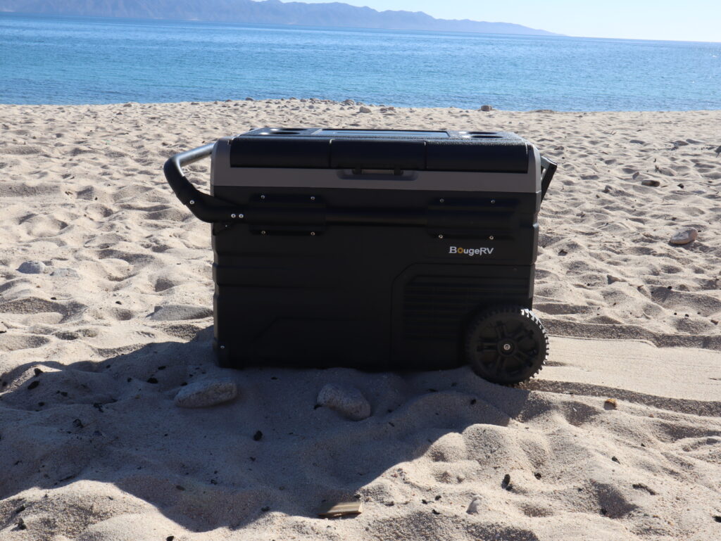 Mobile cooler with wheels on sand in front of water - 12-volt refrgerator