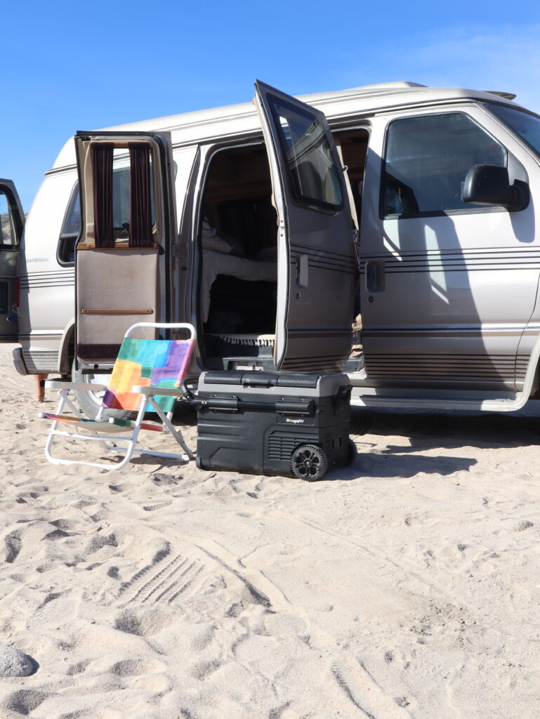 Mobile cooler on sand beside camper van - 12-volt refrigerator